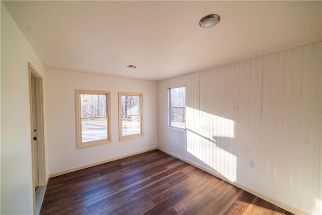 unfurnished room featuring baseboards and dark wood-type flooring