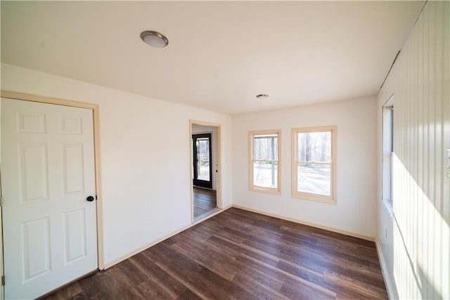 unfurnished room with dark wood-type flooring and baseboards