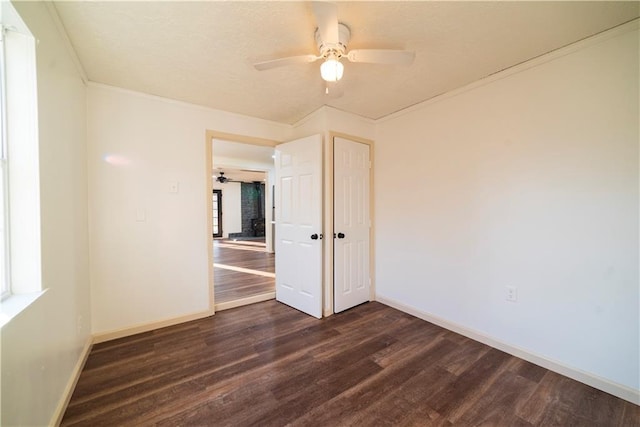 empty room with baseboards, a ceiling fan, dark wood-style flooring, and crown molding