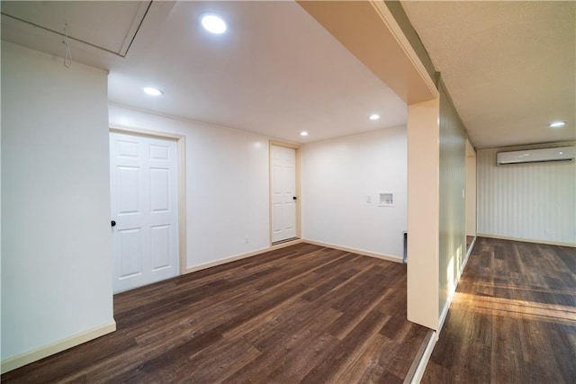 below grade area with recessed lighting, dark wood-style flooring, a wall mounted air conditioner, and baseboards