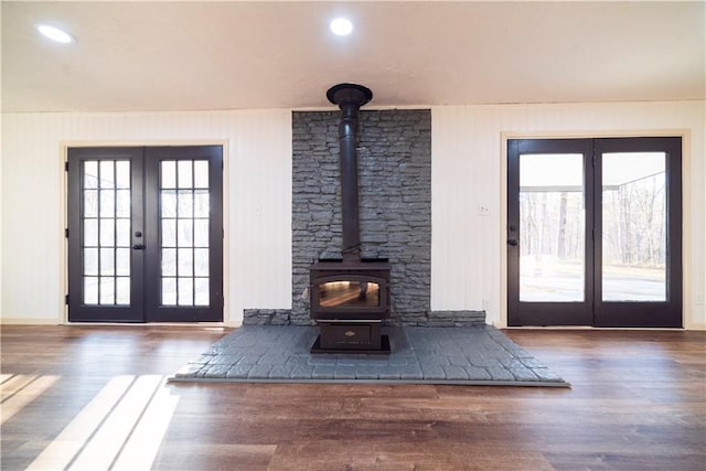 unfurnished living room featuring wood finished floors, a wood stove, and french doors