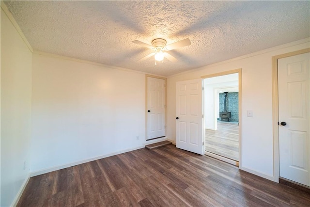 unfurnished bedroom with baseboards, dark wood-style flooring, ceiling fan, ornamental molding, and a textured ceiling