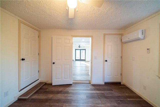 unfurnished bedroom featuring a textured ceiling, baseboards, dark wood-type flooring, and a wall mounted AC