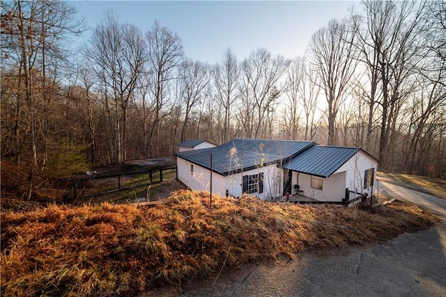 view of side of property featuring driveway, metal roof, and a standing seam roof