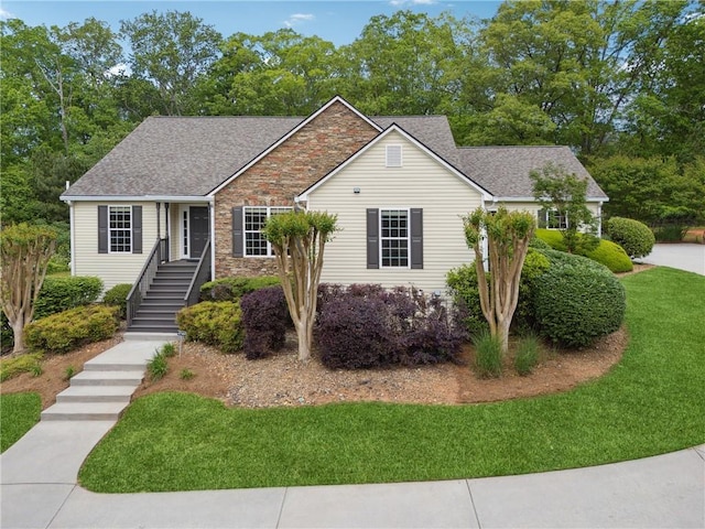 ranch-style home with a shingled roof, stone siding, and a front yard