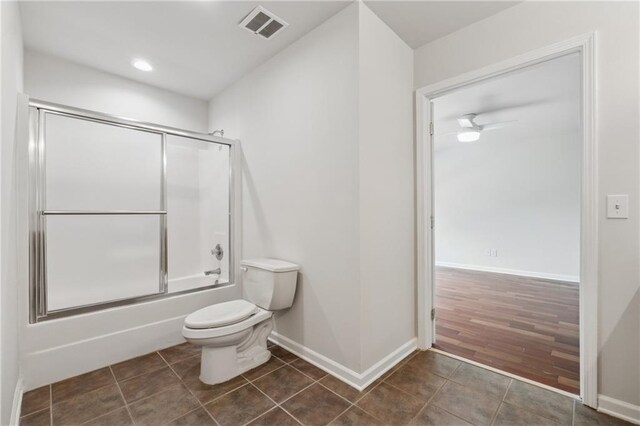 full bath featuring visible vents, tile patterned floors, baseboards, bath / shower combo with glass door, and toilet