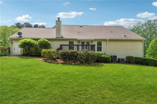 rear view of property with a lawn, a deck, a chimney, and central air condition unit