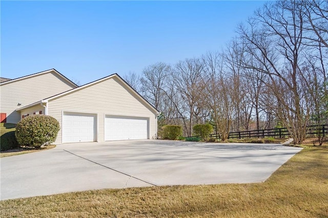 view of property exterior featuring fence, an outbuilding, driveway, and a garage