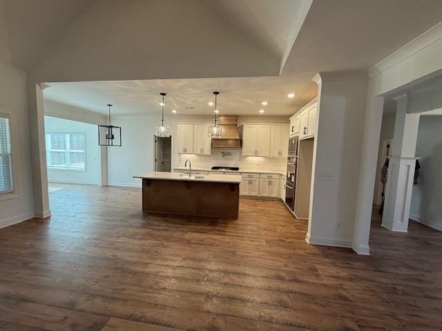 kitchen featuring dark wood-style flooring, open floor plan, light countertops, and an island with sink