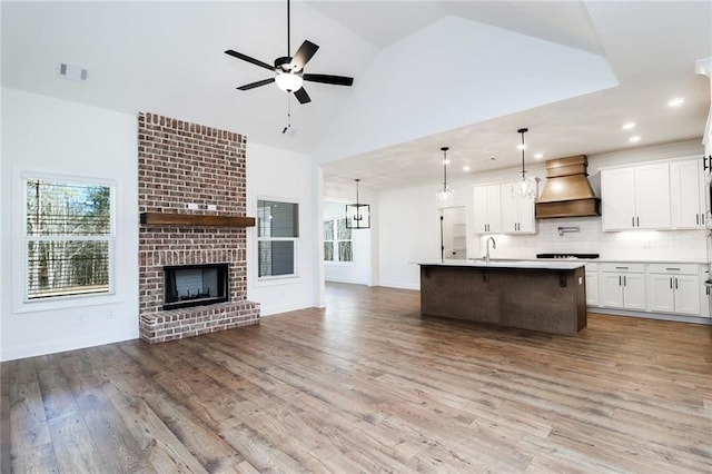 kitchen featuring visible vents, premium range hood, open floor plan, wood finished floors, and a ceiling fan
