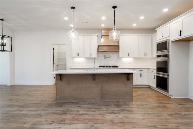 kitchen with premium range hood, built in microwave, tasteful backsplash, and light countertops