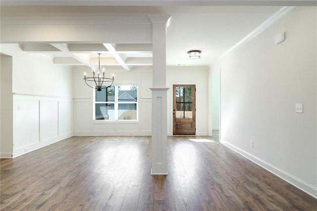 unfurnished dining area featuring beamed ceiling, coffered ceiling, dark wood-style floors, an inviting chandelier, and a decorative wall