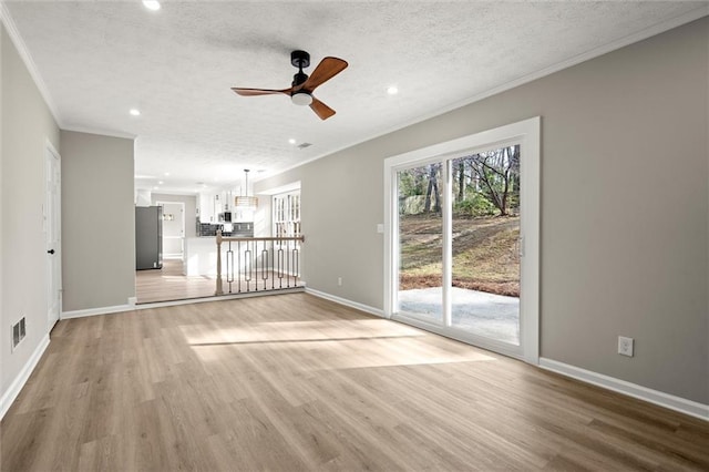 unfurnished living room with crown molding, baseboards, ceiling fan, light wood-type flooring, and a textured ceiling