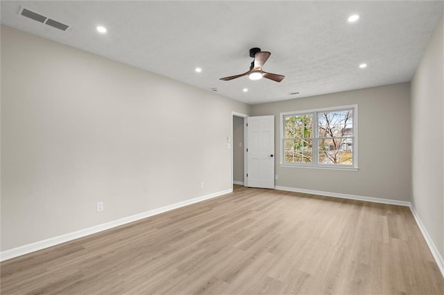 spare room featuring baseboards, light wood-style floors, visible vents, and ceiling fan