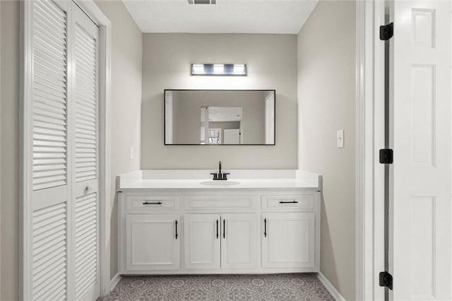 bathroom featuring visible vents, baseboards, and vanity