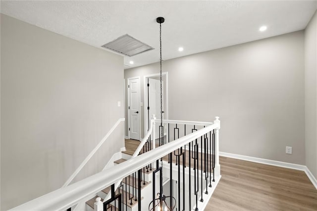 hall featuring wood finished floors, recessed lighting, an upstairs landing, and baseboards