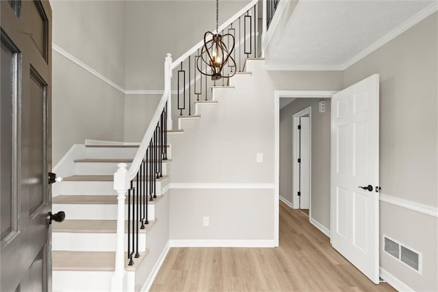 interior space featuring visible vents, ornamental molding, wood finished floors, stairway, and baseboards