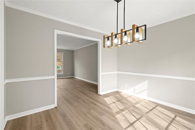 unfurnished room featuring baseboards, wood finished floors, an inviting chandelier, and ornamental molding