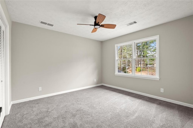 carpeted empty room featuring visible vents, a ceiling fan, baseboards, and a textured ceiling