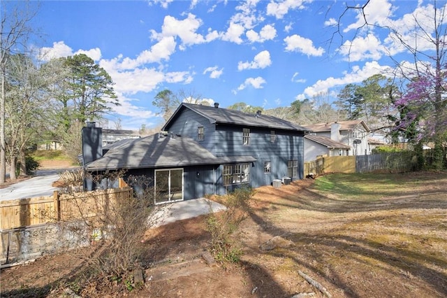 rear view of property featuring a yard, driveway, and fence