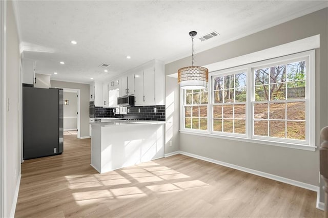 kitchen featuring visible vents, backsplash, stainless steel appliances, light wood finished floors, and baseboards