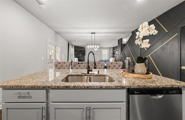 kitchen featuring sink, stainless steel dishwasher, and light stone counters