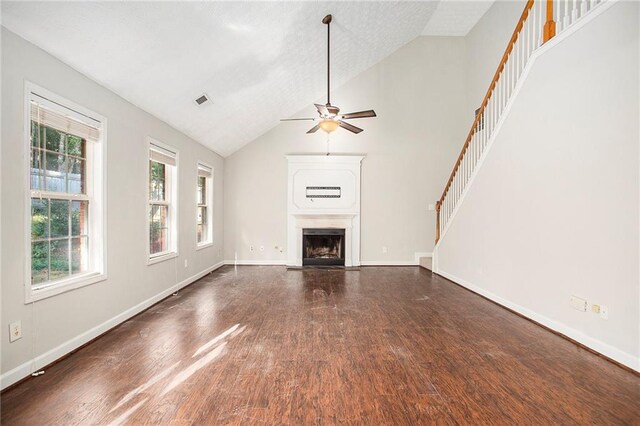 unfurnished living room with high vaulted ceiling, ceiling fan, dark hardwood / wood-style floors, and a textured ceiling