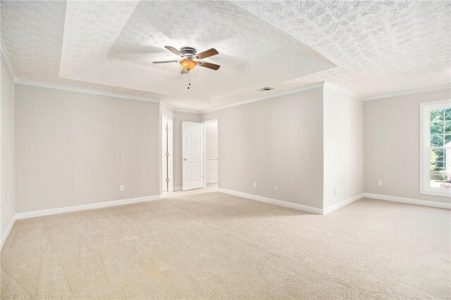 carpeted empty room with crown molding, a raised ceiling, a textured ceiling, and ceiling fan