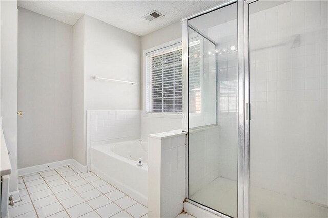 bathroom with a textured ceiling, tile patterned floors, and shower with separate bathtub