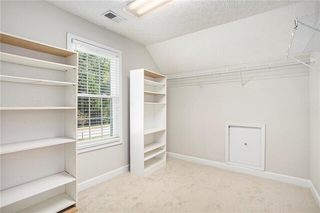 spacious closet with vaulted ceiling and carpet floors