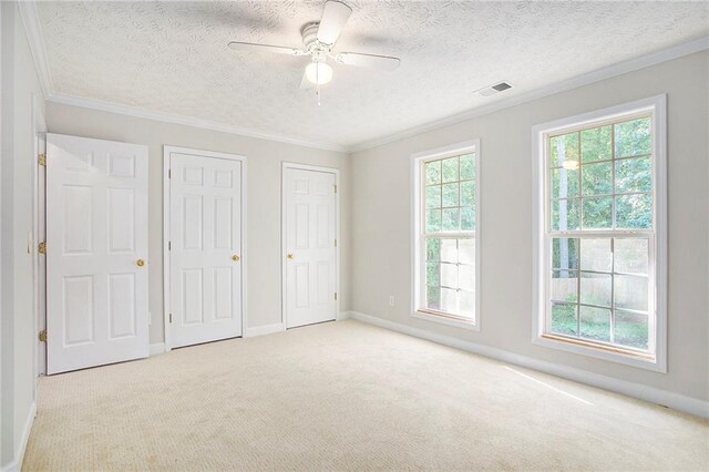 unfurnished bedroom featuring multiple windows, ceiling fan, and light colored carpet