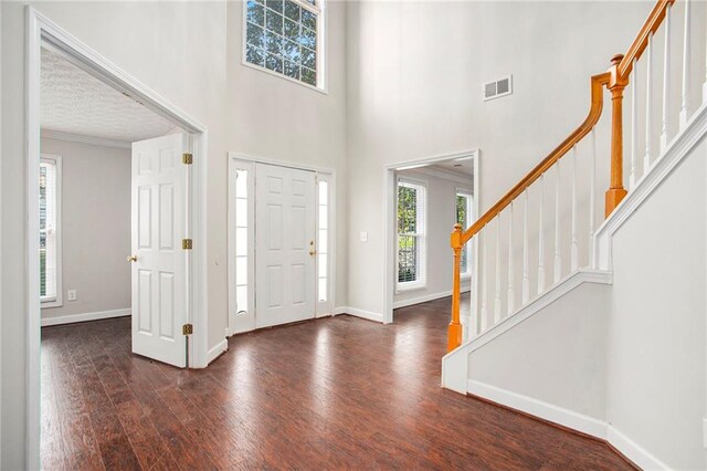 foyer with dark wood-type flooring, a textured ceiling, and ornamental molding