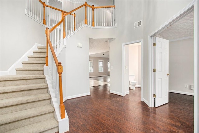 interior space with a towering ceiling, dark hardwood / wood-style flooring, and a textured ceiling