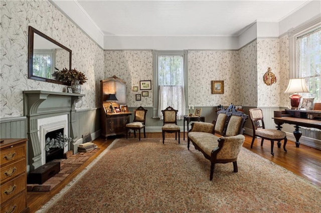 sitting room with dark hardwood / wood-style flooring, crown molding, and a healthy amount of sunlight