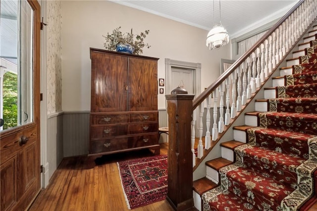 stairway featuring crown molding, hardwood / wood-style flooring, and a notable chandelier