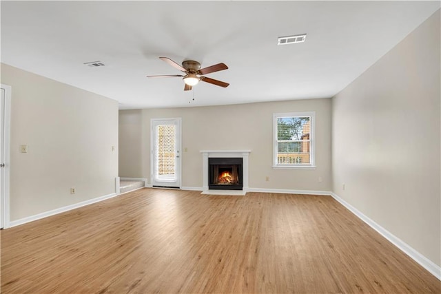 1368 Poplar Pointe SE, Smyrna, GA 30082 - unfurnished living room featuring a ceiling fan, light wood-style floors, plenty of natural light, and a warm lit fireplace