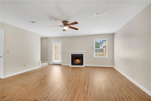 1368 Poplar Pointe SE, Smyrna, GA 30082 - unfurnished living room featuring a ceiling fan, light wood-style floors, plenty of natural light, and a warm lit fireplace