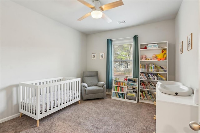 bedroom featuring a crib, carpet floors, and ceiling fan