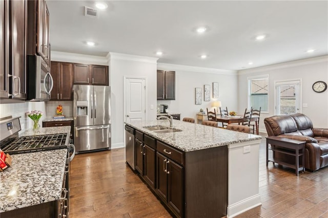 kitchen with stainless steel appliances, sink, a kitchen island with sink, and hardwood / wood-style floors