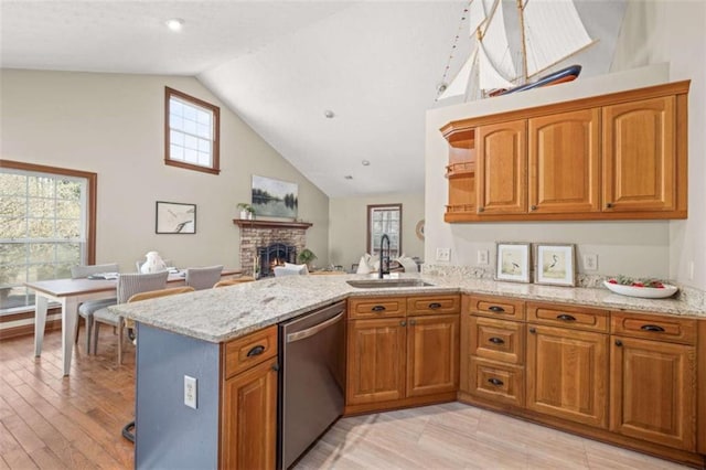 kitchen featuring dishwasher, a peninsula, brown cabinetry, and a sink