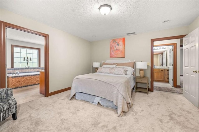 bedroom with a textured ceiling, connected bathroom, light carpet, visible vents, and baseboards