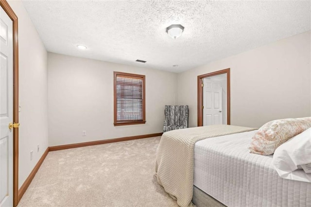 bedroom featuring visible vents, baseboards, a textured ceiling, and light colored carpet