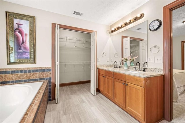 bathroom with a textured ceiling, double vanity, and a sink