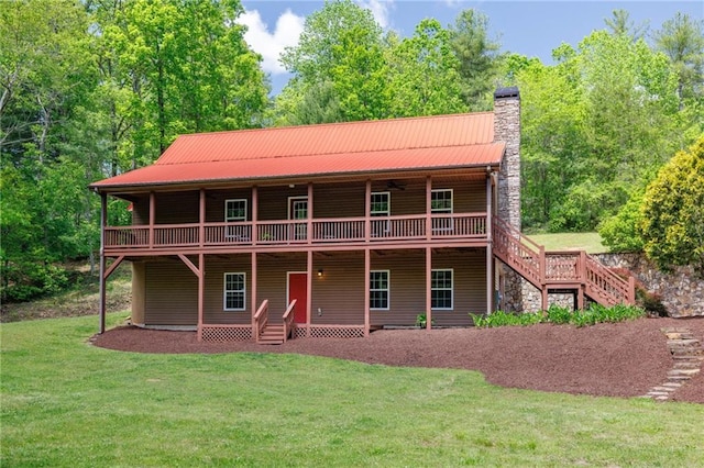 back of house with a deck, metal roof, a yard, and a chimney