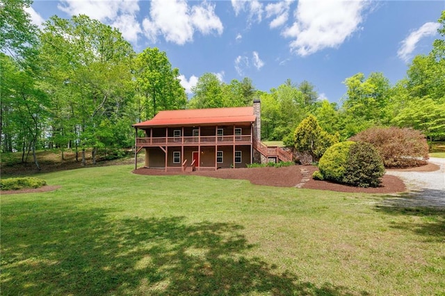 rear view of house with a deck, a yard, a chimney, and stairs