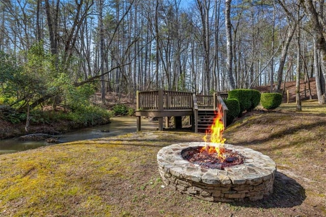 view of yard featuring an outdoor fire pit, a wooden deck, and stairs