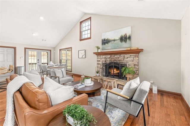 living room with french doors, a fireplace, plenty of natural light, and light wood-style flooring