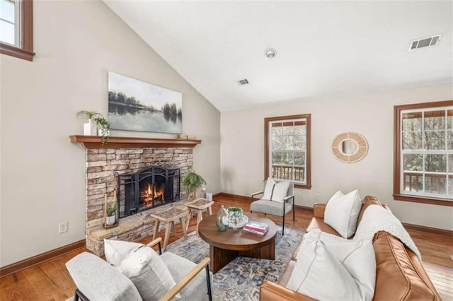 living room featuring visible vents, wood finished floors, and a stone fireplace