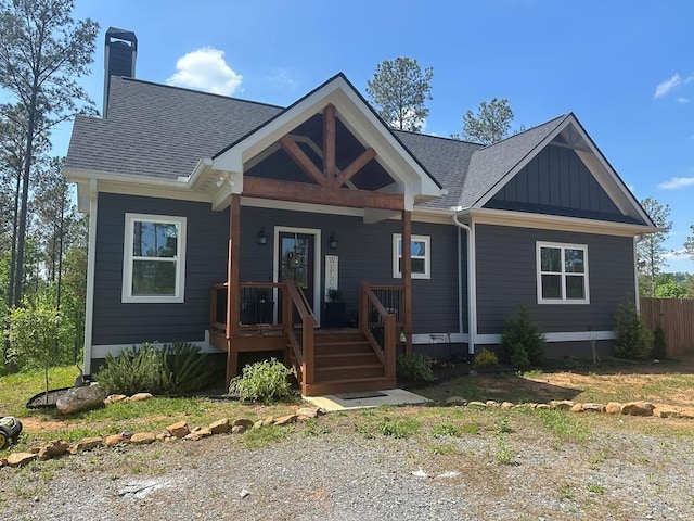 view of front facade with a porch, a shingled roof, board and batten siding, and a chimney