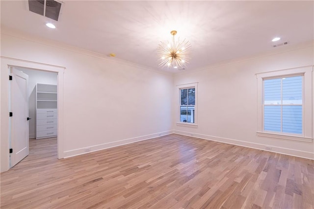 empty room with light wood-style floors, visible vents, and crown molding